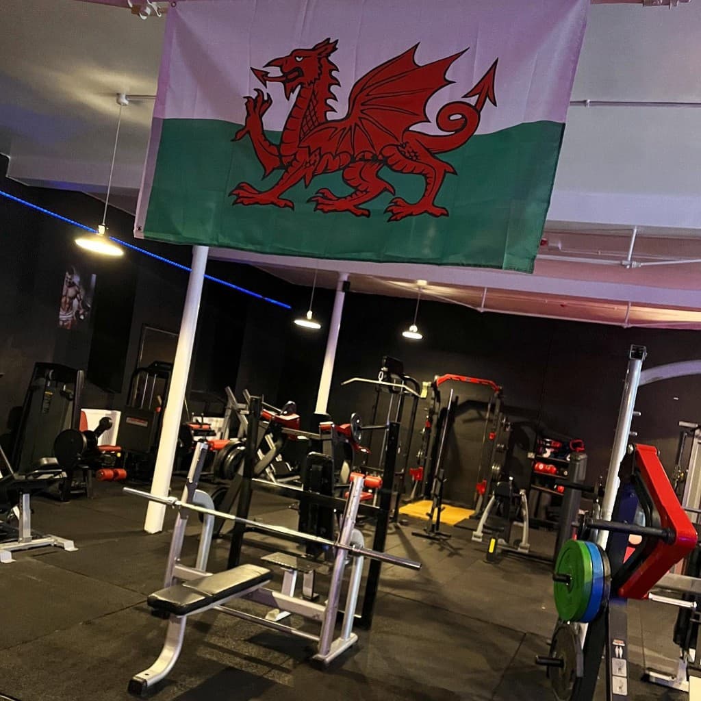 Free weights area with Welsh flag and bench press at Big Dragons Gym